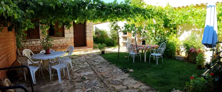 El jardín bajo la parra, con la mesa y el muro de piedra