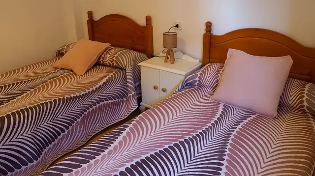 Dormitorio con dos camas individuales en tonos malva