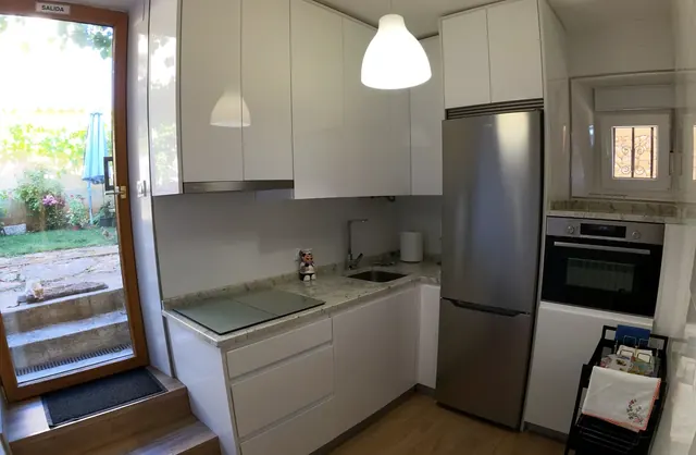 Cocina equipada con nevera, horno y salida al jardín